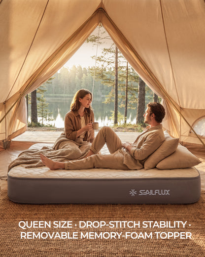 Couple relaxing on the Voyage CloudTop queen air mattress inside a canvas bell tent beside a lake at sunrise